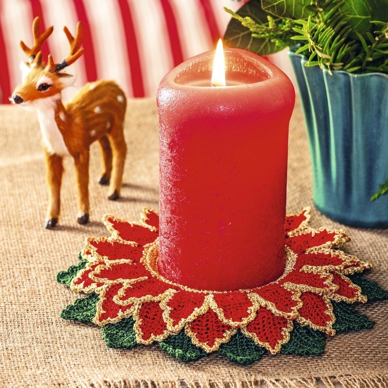 Gehäkelter roter Kerzenuntersetzer im Weihnachtsstern-Design mit goldfarbener Kante und grünen Blättern unter brennender roter Stumpenkerze