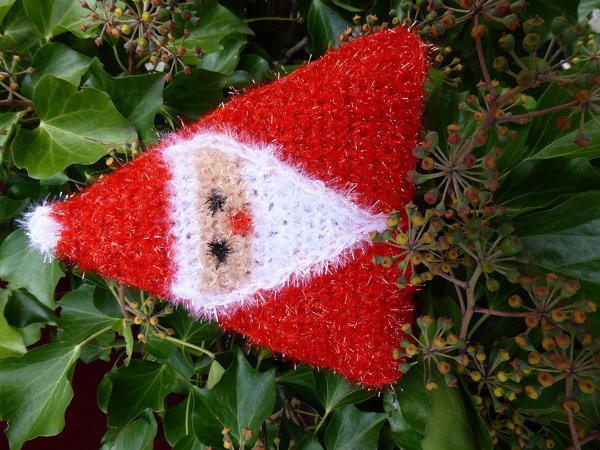 Gehäkelter roter Weihnachtswichtel mit weißem Bart auf Efeu
