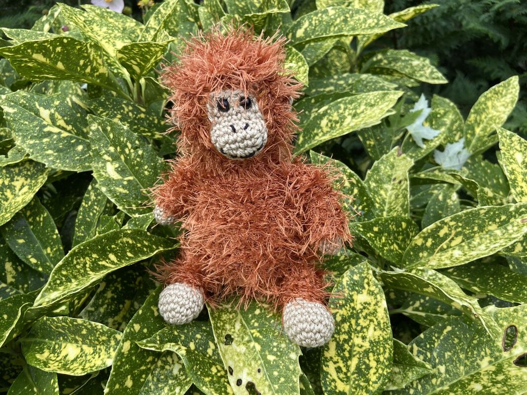 Nahaufnahme eines braunen flauschigen Amigurumi mit sichtbarer Maschenstruktur und beiger Schnauze