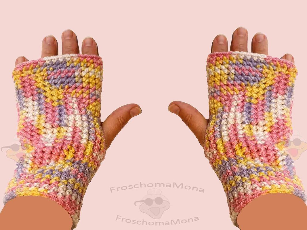 Fingerlose, gehäkelte Handschuhe in Rosa, Gelb, Lila und Weiß an zwei Händen.