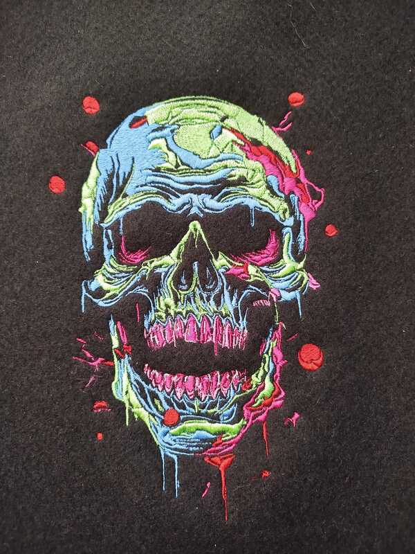 Bunte Stickerei eines schmelzenden Totenkopfs in Neonfarben auf schwarzem Stoff