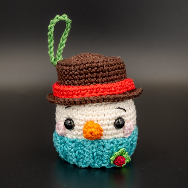Gehäkelter Schneemann-Anhänger mit braunem Hut und türkisfarbenem Schal
