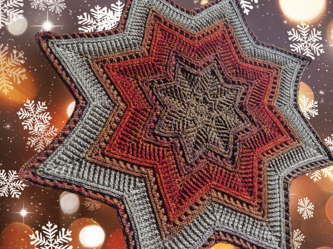Handgehäkeltes sternförmiges Deckchen mit mehrfarbigem Verlauf und feinen Häkelmustern auf weihnachtlichem Hintergrund mit Lichtern und Schneeflocken.