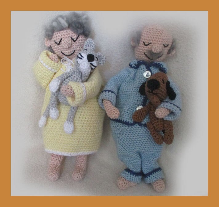 Crocheted elderly couple amigurumi dolls in yellow robe and blue pajamas holding a gray cat and a brown dog