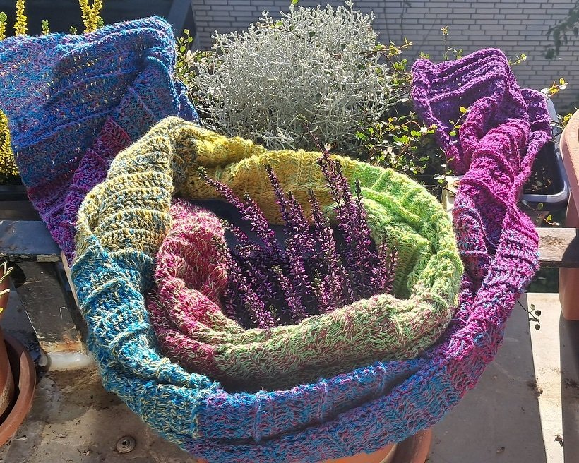 Mehrfarbiger Häkel-Schal mit markantem Strukturmuster, auf Balkon arrangiert