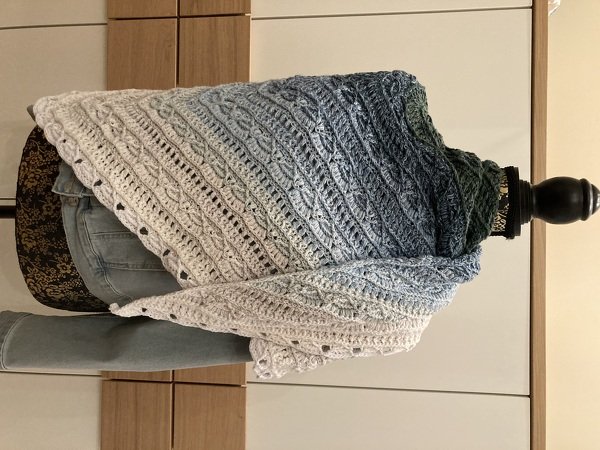 Gehäkeltes dreieckiges Tuch mit Farbverlauf in Weiß, Blau und Grün auf einer Schneiderpuppe drapiert