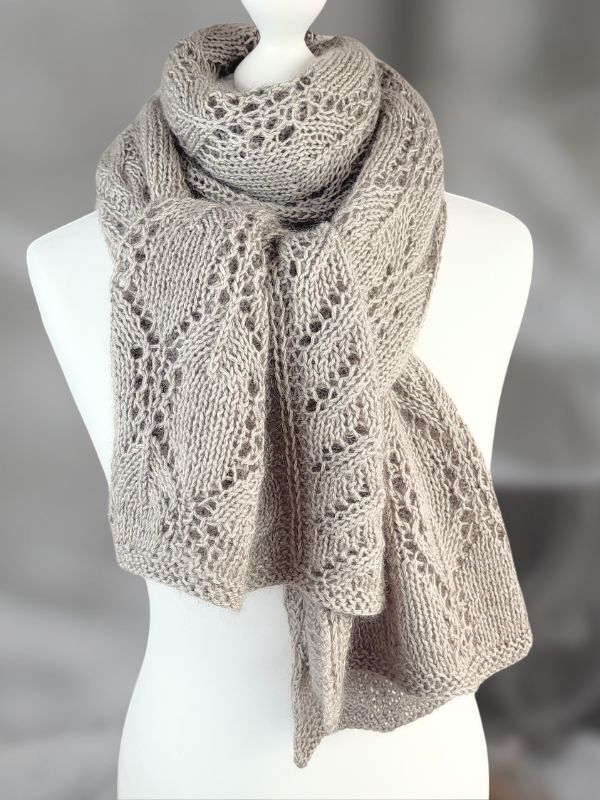 Sandgrauer gestrickter Schal mit Blatt‑Lochmuster, lässig um eine Schaufensterpuppe gelegt