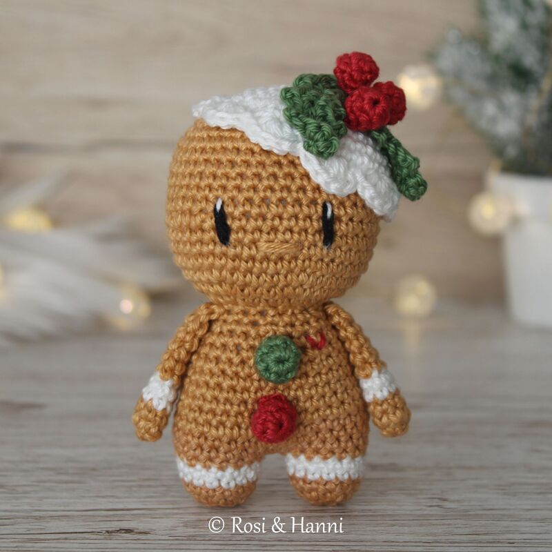 Gehäkelte Lebkuchen-Amigurumi mit Zuckergussrand, roten und grünen Knöpfen und Stechpalme