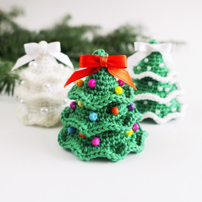Drei kleine gehäkelte Weihnachtsbäume in Grün und Weiß mit Perlen und Schleifen