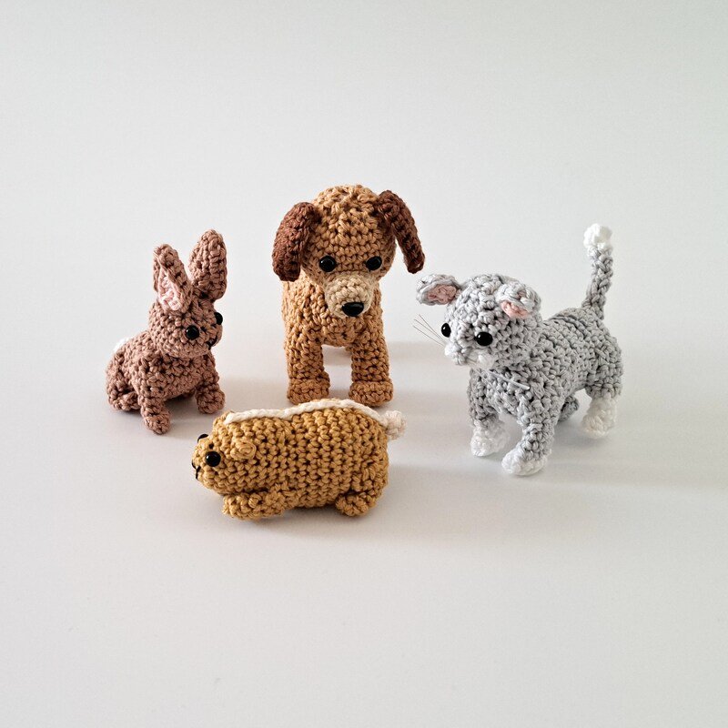 Four amigurumi crochet animals: brown dog, gray cat, brown rabbit, and small tan rodent on white background.