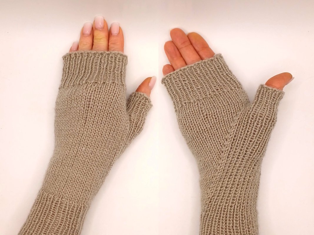 Paar beige gestrickte fingerlose Armstulpen mit Daumenöffnungen auf hellem Hintergrund