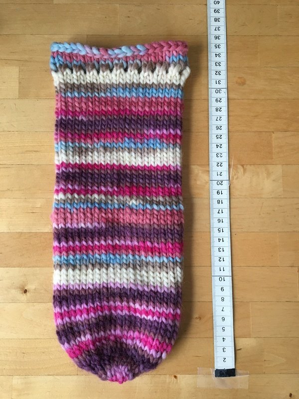 Mehrfarbige Strickprobe mit Rippenmuster und Maßband zur Längenmessung