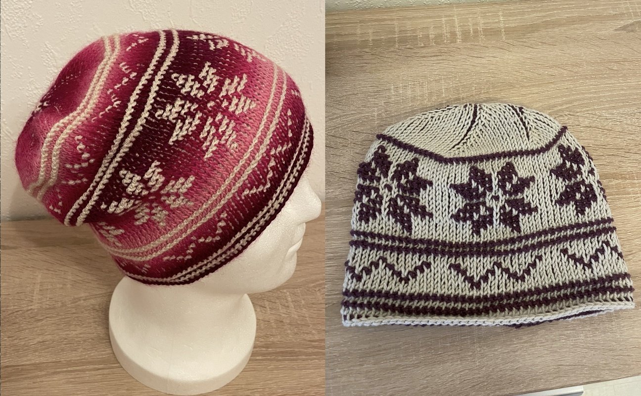 Zwei gestrickte Mützen mit Schneeflockenmustern, pink-rot auf Schaufensterkopf und beige-lila flach liegend.