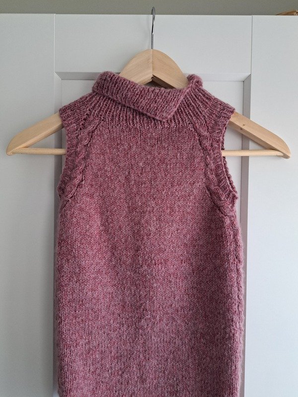 Heathered pink sleeveless children's knit top with folded collar on wooden hanger