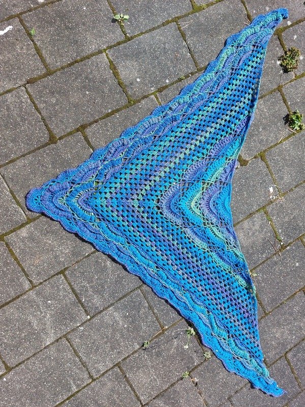 Dreieckstuch mit Netzgitter und Muschelrand in Blau‑Türkis auf Steinboden