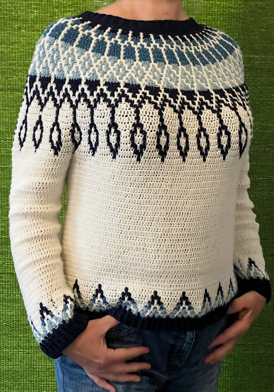 Weißer gehäkelter Damenpullover mit blauen geometrischen Mustern am Rundhalsausschnitt, an Ärmeln und am Saum.