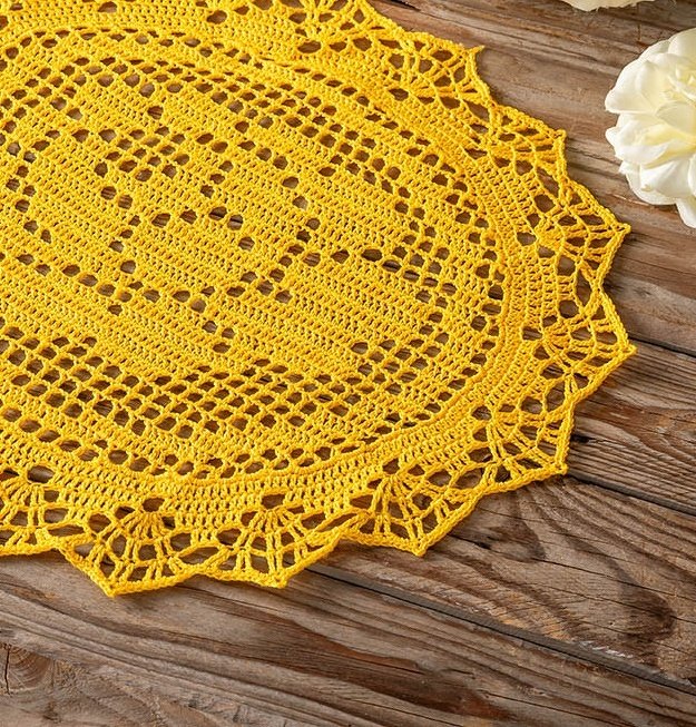 Rundes gelbes gehäkeltes Deckchen mit Spitzenrand auf Holzoberfläche