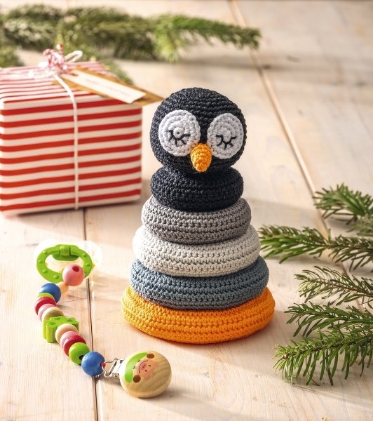 Gehäkeltes Stapelspiel aus Ringen mit schwarzem Pinguin-Kopf und abgestuften grauen bis orangefarbenen Ringen