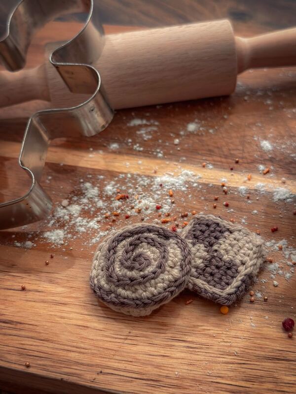 Gehäkelte Plätzchen als Tischdeko auf Holzbrett mit Backutensilien
