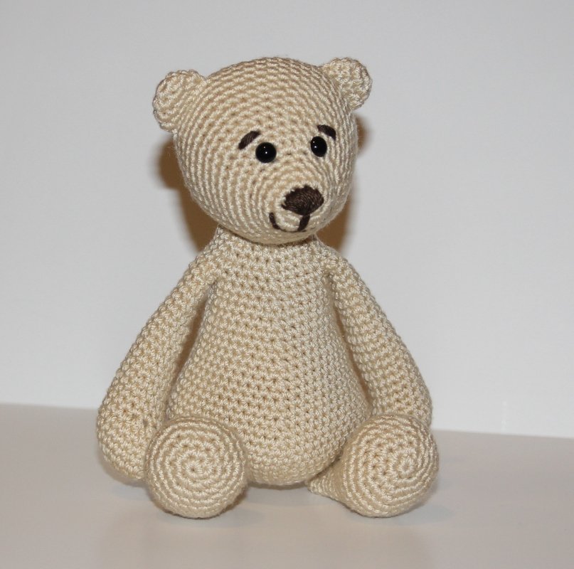 Beiger gehäkelter Amigurumi-Teddybär mit schwarzen Augen und gestickter Nase, sitzend