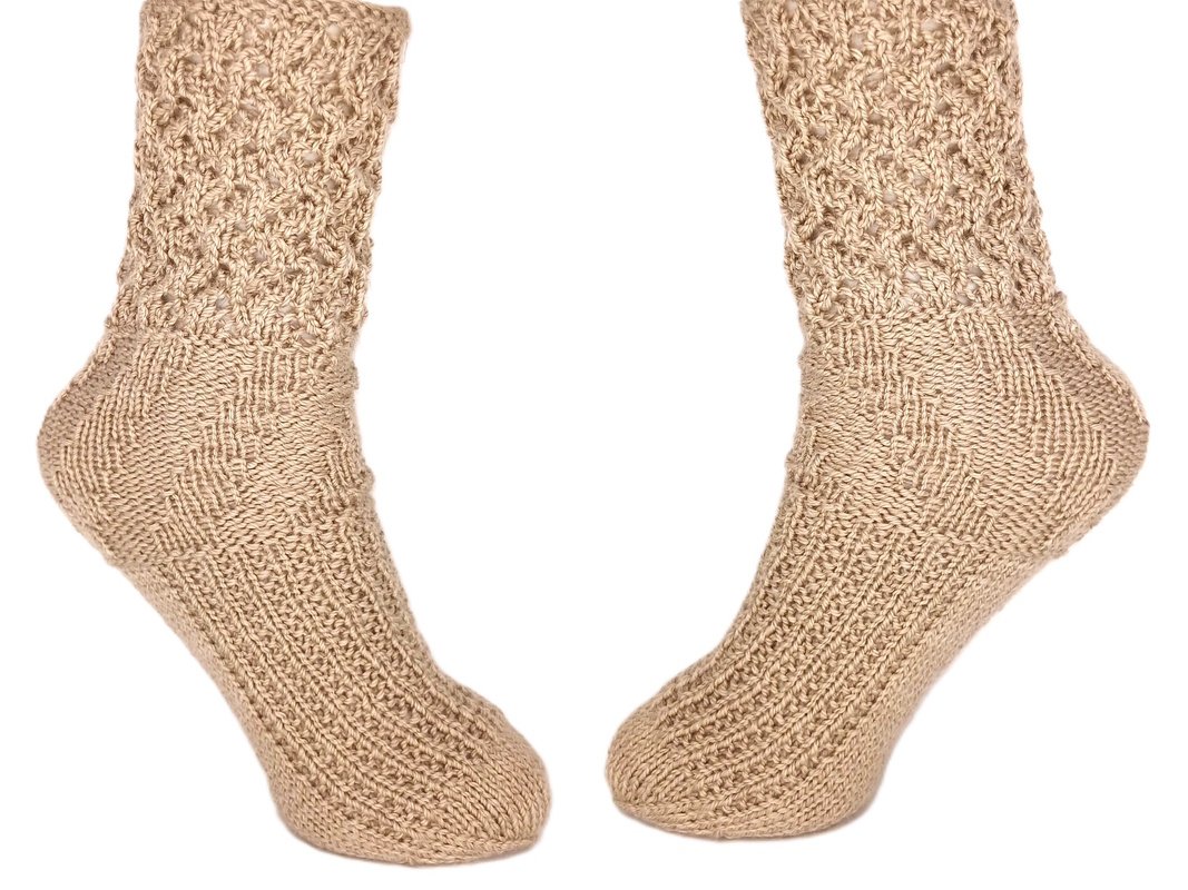 Zwei beige gestrickte Socken mit Lochmuster am Schaft und strukturiertem Fuß auf weißem Hintergrund.
