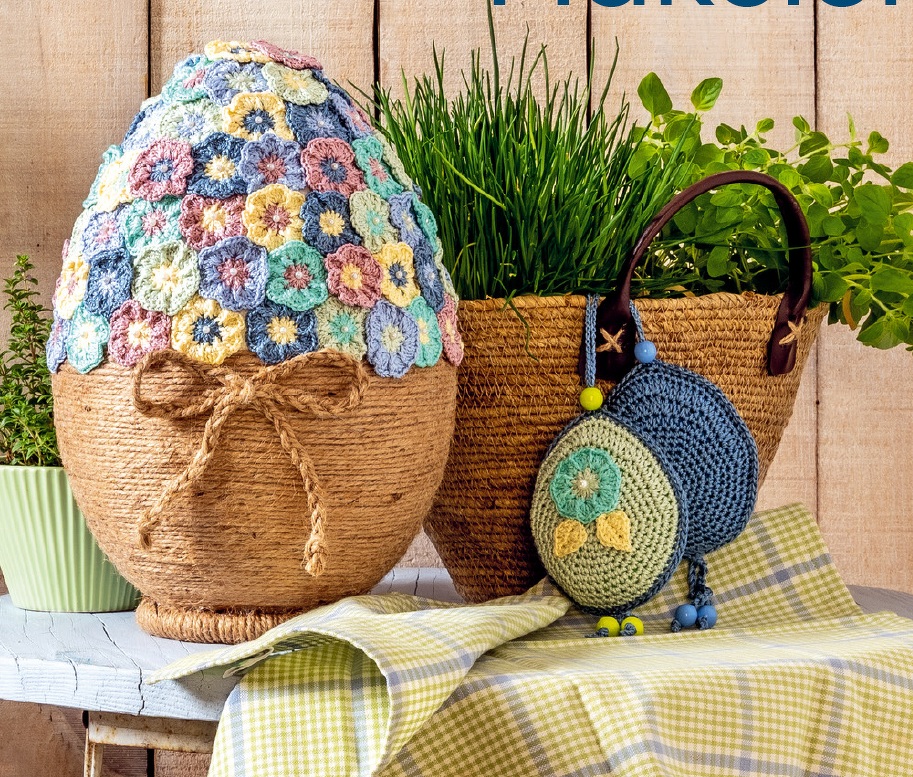 Großes Deko-Ei mit einer Haube aus bunten Häkelblüten und Schnur-Umwicklung, umgeben von Kräutern und kleinen gehäkelten Eiern