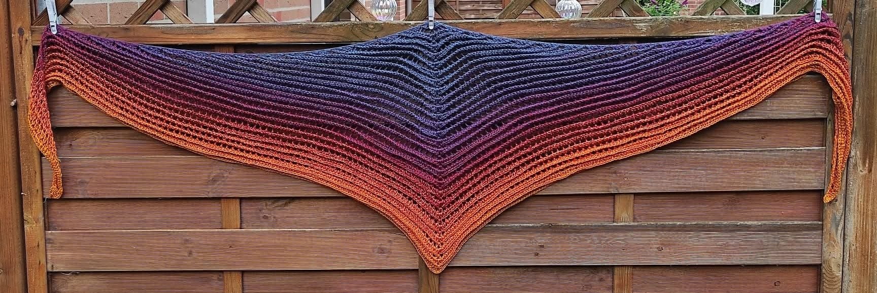 Gehäkeltes Dreieckstuch in Blau‑Lila‑Orange an einem Holzzaun