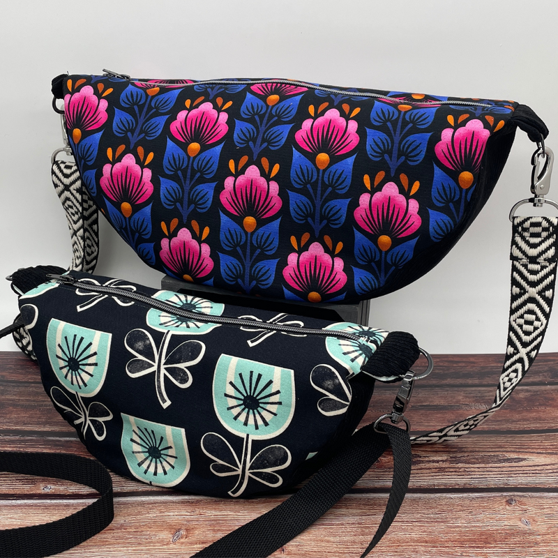 Zwei halbmondförmige Taschen mit Blumenmustern, Reißverschluss und abnehmbaren Tragegurten