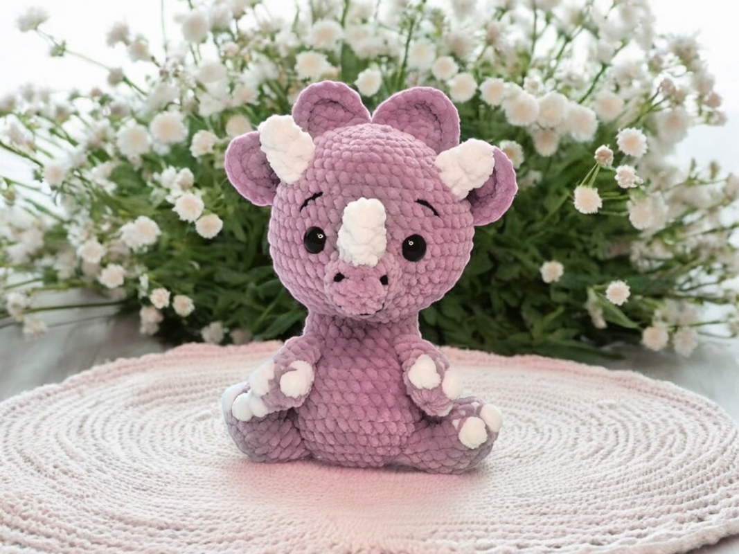 Gehäkeltes Triceratops-Amigurumi in Flieder mit weißen Hörnern und Pfoten