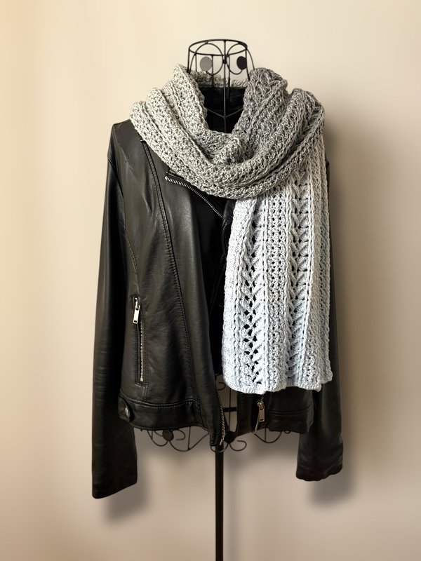 Light gray lacy crochet scarf wrapped around a wire mannequin wearing a black leather jacket