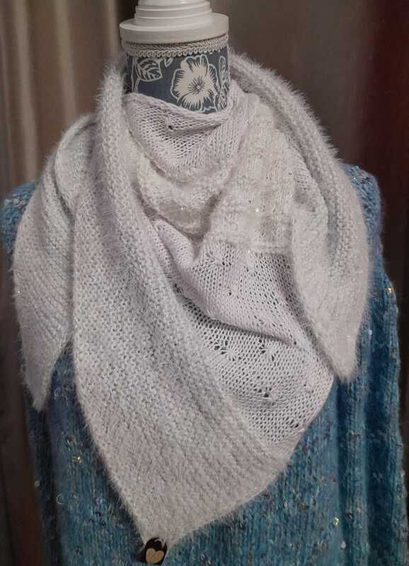 Weißes gestricktes Dreieckstuch mit Lochmuster und dezentem Glitzer, auf einer Schaufensterpuppe drapiert.