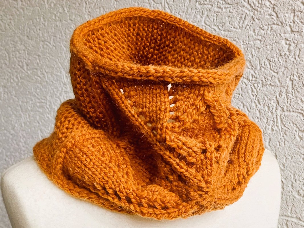 Gestrickter Loop-Schal in Rostorange mit Ajour- und Zopfmuster auf Schneiderpuppe