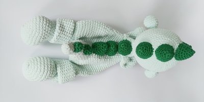 Mintgrüner gehäkelter Amigurumi-Drache von oben mit dunklen, runden Rückenschuppen