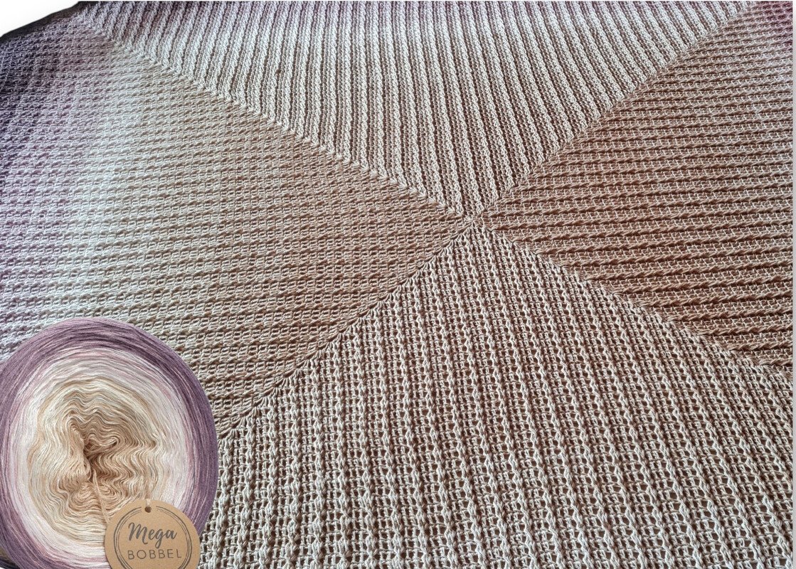 Nahaufnahme einer gehäkelten Decke in Natur- und Rosétönen mit geometrischem Strukturmuster