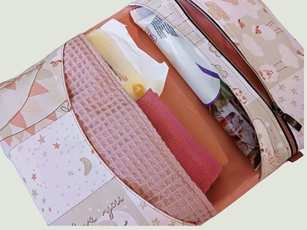 Pastellfarbene Wickeltasche offen mit Feuchttücherpack, rosa Waffeltuch und weichem Tuch