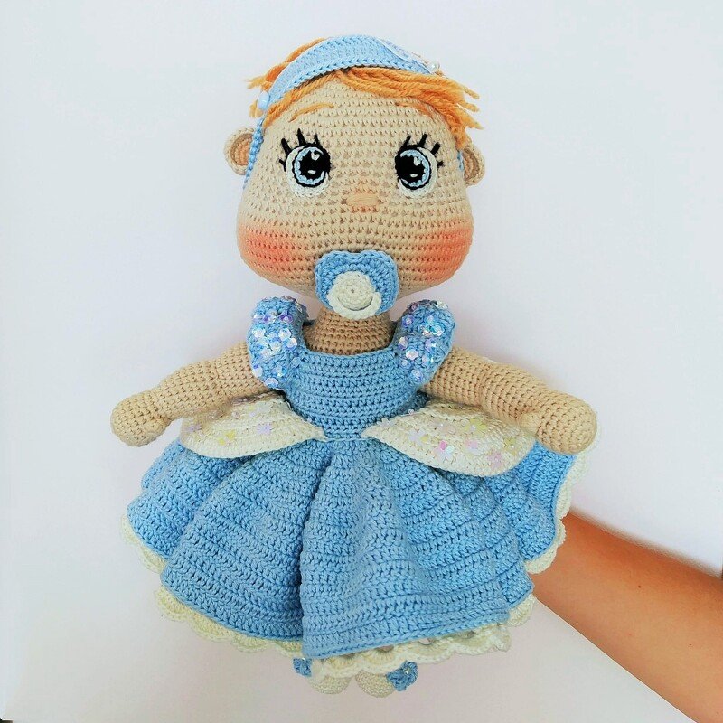 Crochet amigurumi baby doll in a light blue layered dress with matching headband and blue pacifier