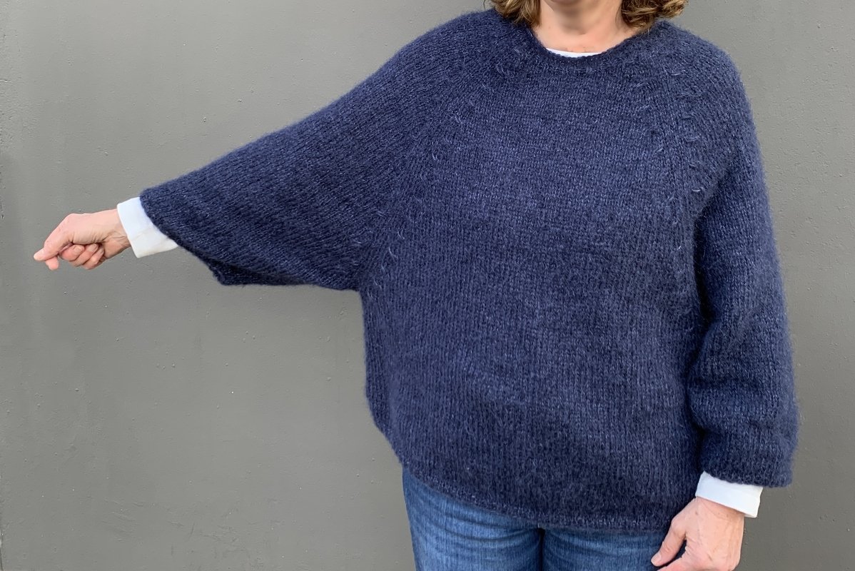 Detailansicht eines dunkelblauen gestrickten Oversize-Pullovers mit Raglannähten und lockerem Fall.