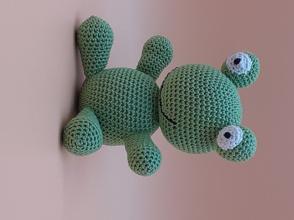 Grüner gehäkelter Amigurumi-Frosch mit aufgesetzten Augen