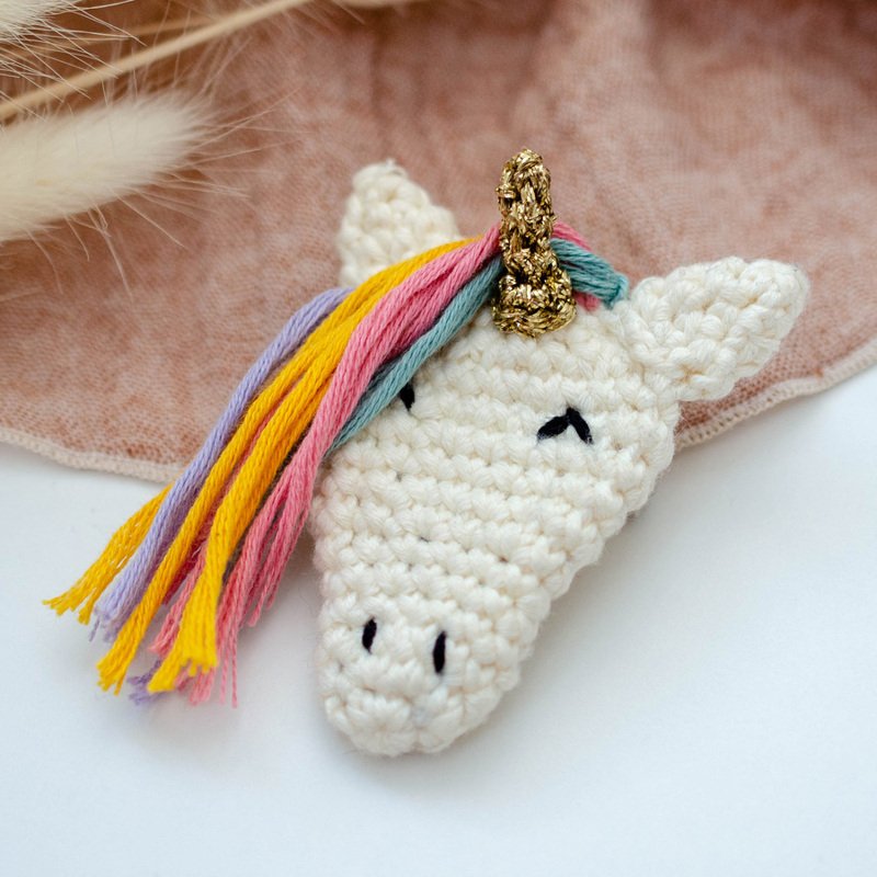 Kleiner schnell gehäkelter Einhornkopf mit bunten Garnsträhnen und goldfarbenem Horn