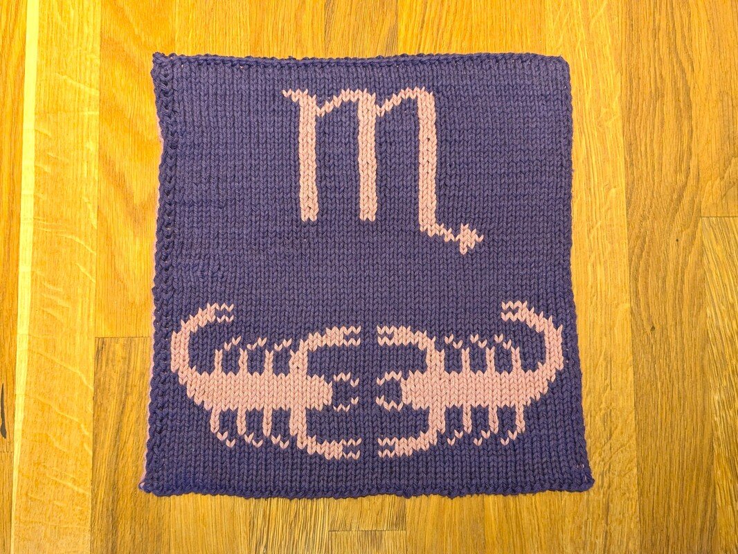 Handgestrickter Topflappen in Violett mit rosa Skorpionmotiv und Sternzeichen-Glyphe