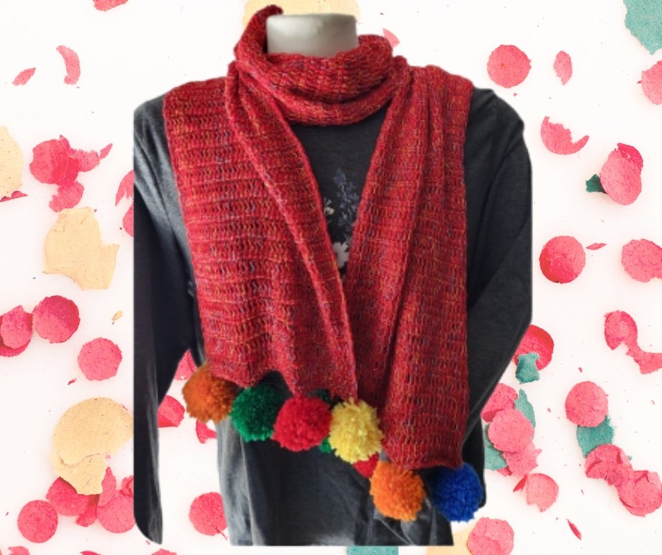 Red crocheted scarf with orange, green, yellow, blue and red pom-poms on a mannequin.