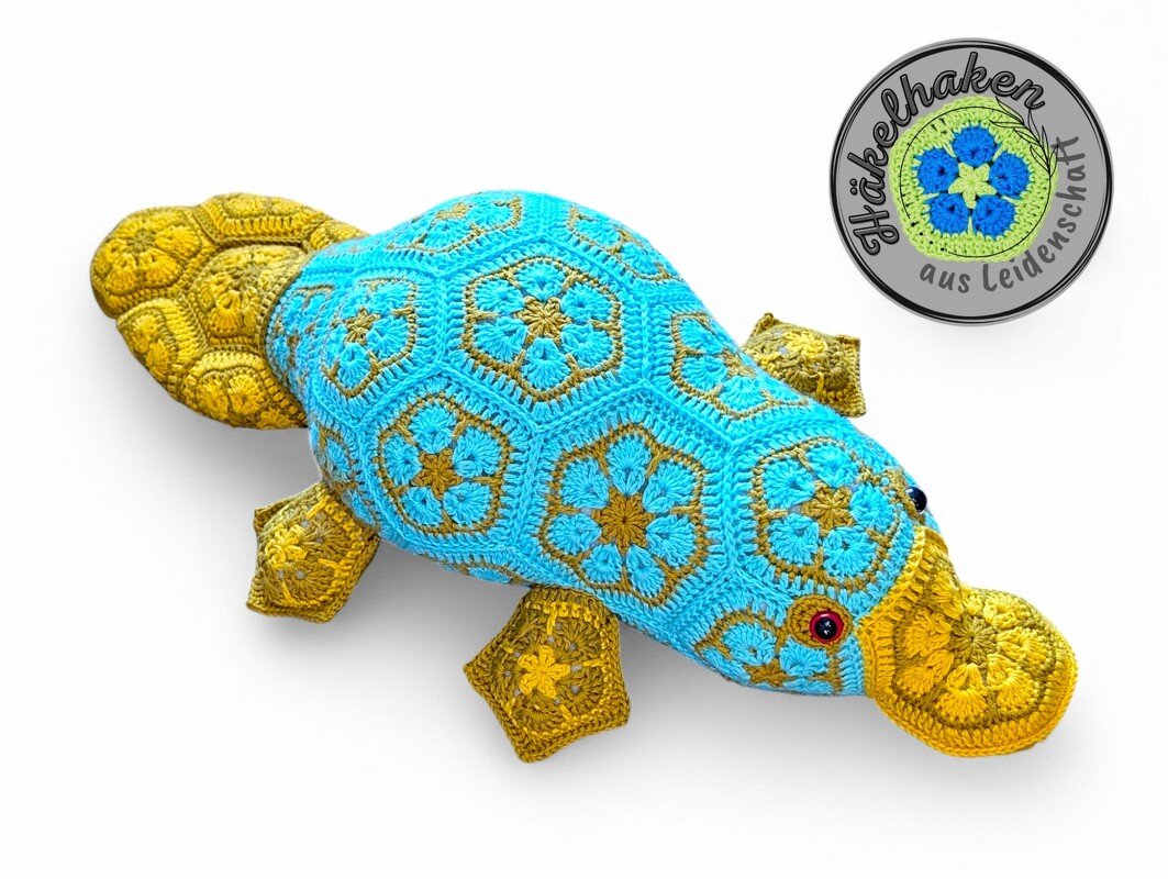 Blue and yellow crocheted platypus made from African flower granny motifs on a white background.