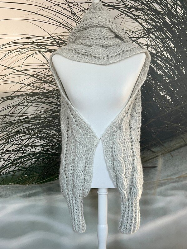 Hellgrauer gehäkelter Kapuzenschal mit Zopfmuster auf Schaufensterpuppe