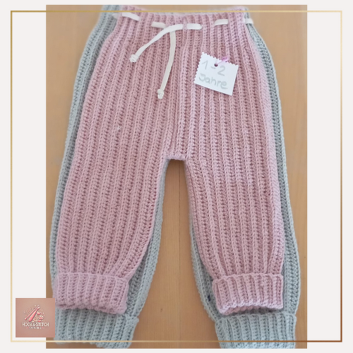 zwei gehäkelte Kleinkinderhosen in Rosé und Grau übereinander, mit Kordelzug und Umschlagbündchen