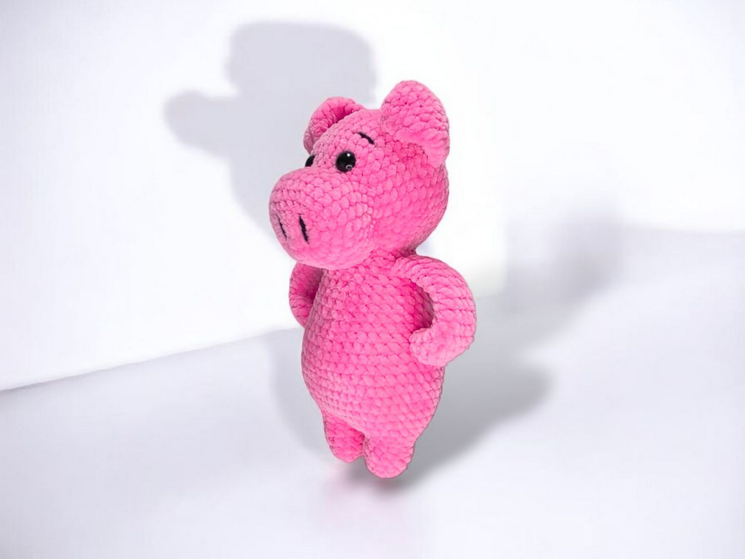 Rosa gehäkeltes Amigurumi‑Schwein aus kuscheligem Garn, stehend mit Armen an der Seite
