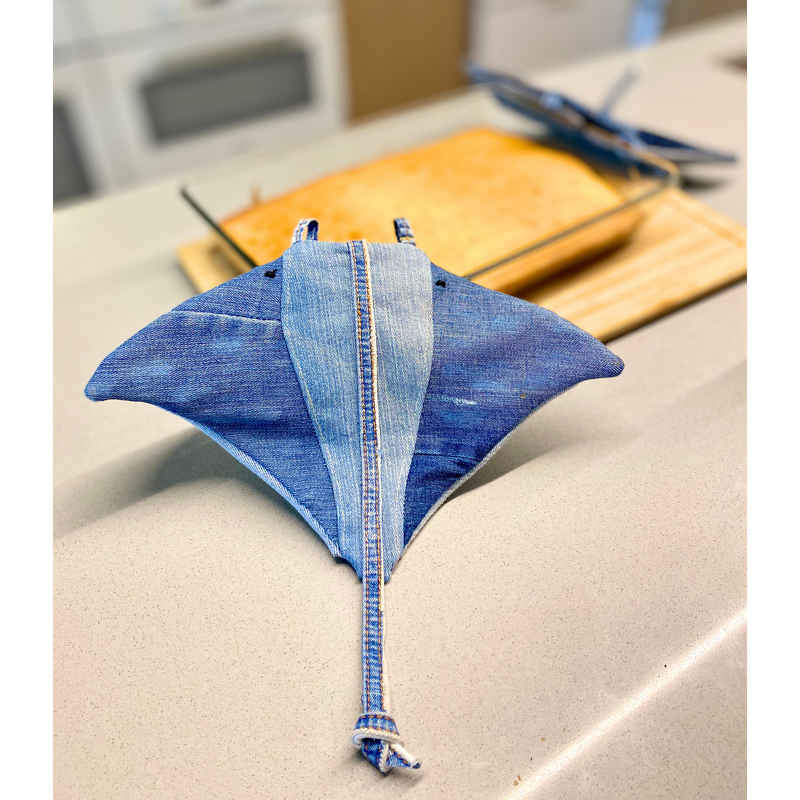 Stingray-shaped denim potholder with central seam and tail loop on countertop