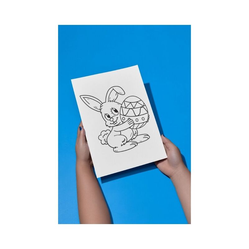 Hände halten ein Blatt Papier mit einer Schwarz-Weiß-Zeichnung eines lächelnden Osterhasen, der ein verziertes Ei hält, vor blauem Hintergrund.