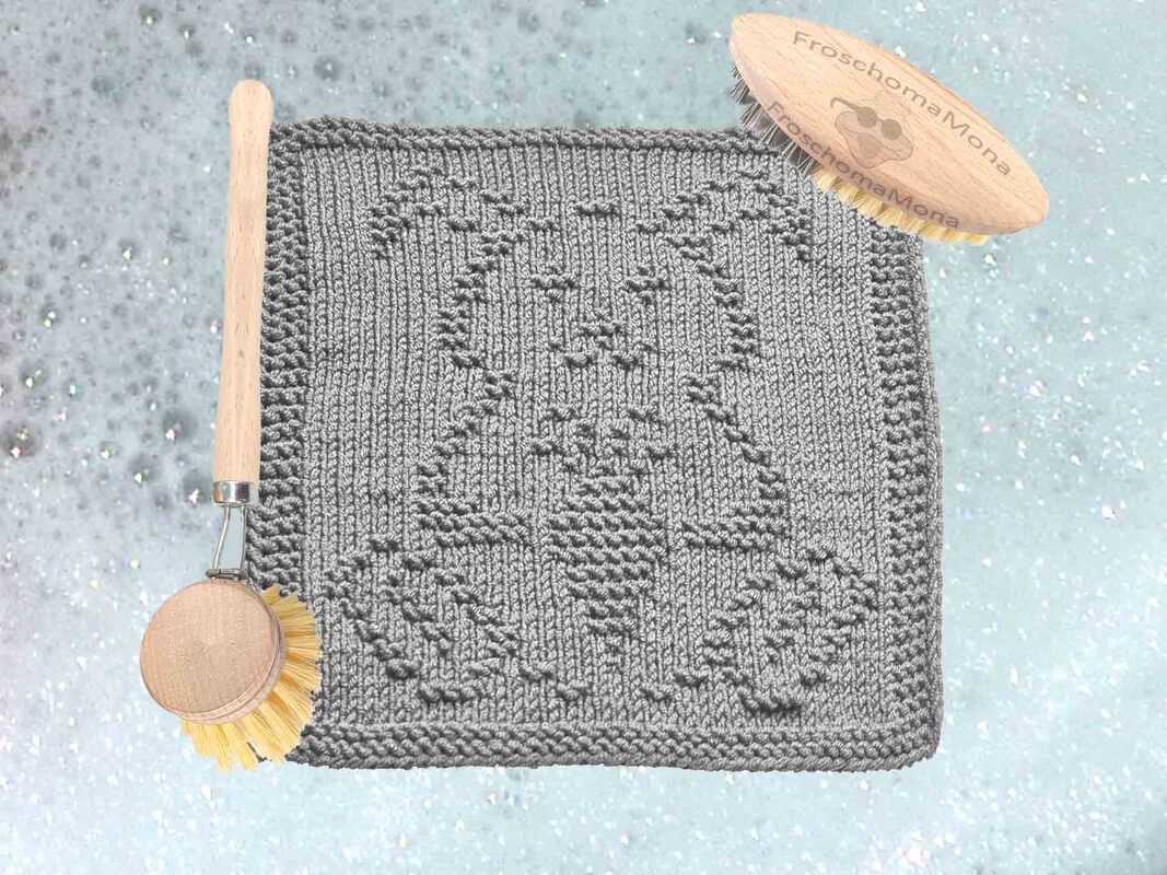 Gestricktes graues, quadratisches Deckchen mit Relief‑Ei und Blumenmuster auf hellem Hintergrund mit Seifenblasen‑Effekt.