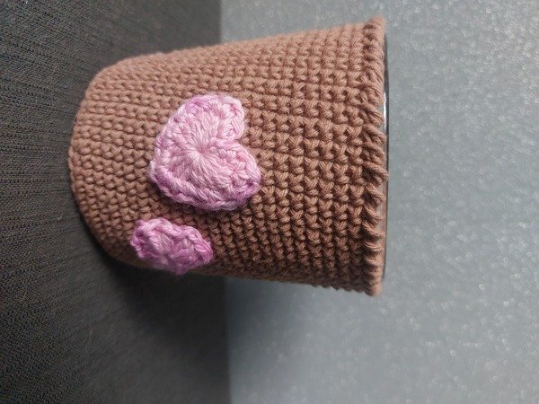 Beiger Häkelüberzug verziert mit zwei kleinen rosa Häkelherzen