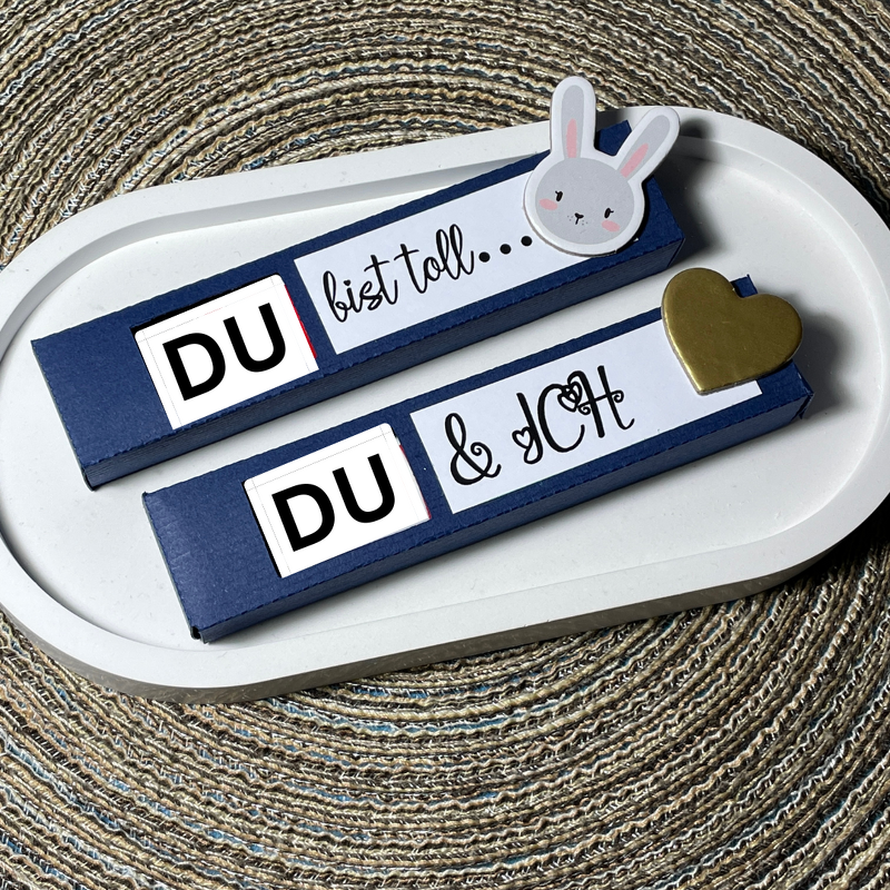 Dunkelblaue Geschenkboxen mit weißen Plott-Etiketten 'DU bist toll' und 'DU & ICH' auf ovalem Tablett